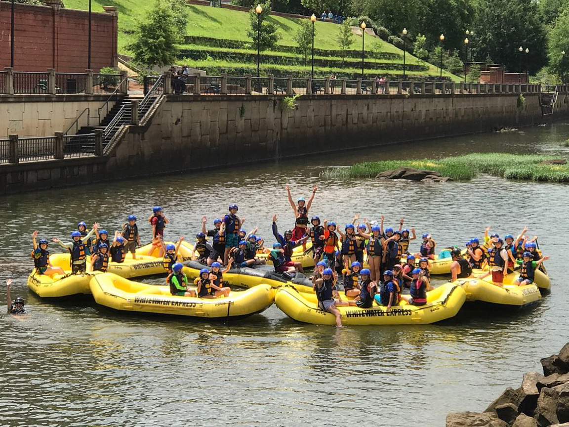 Kids on whitewater rafts at camp